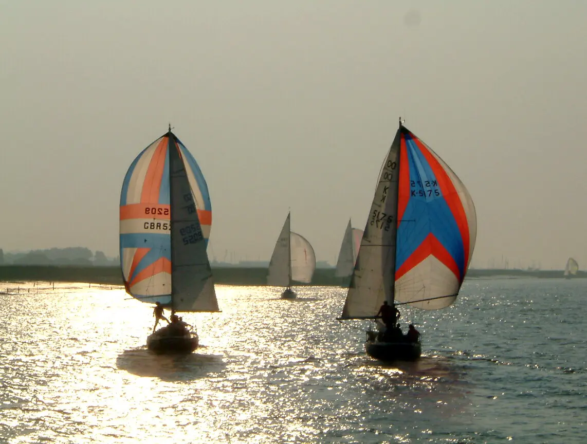 Yachts racing under coloured spinnakers on the River Crouch at sunset