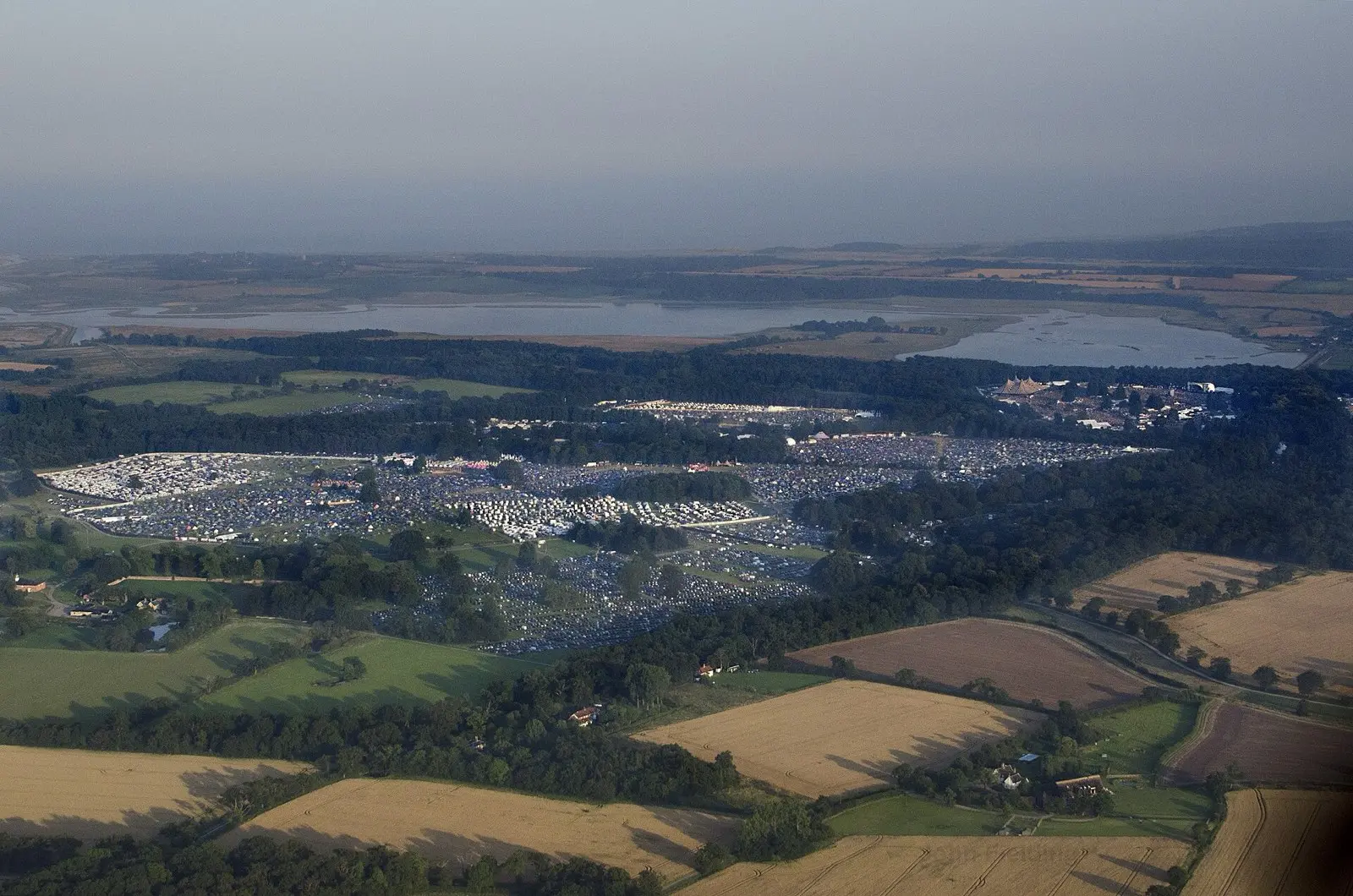 Aerial view of Latitude Festival at Henham Park showing camping fields, caravan rows and the main arena beside woodland