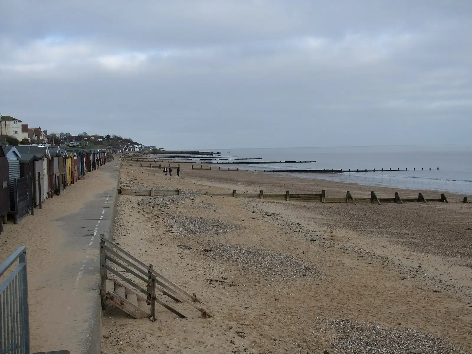 A long line of beach huts and wooden groynes stretching along the sandy beach at Walton-on-the-Naze